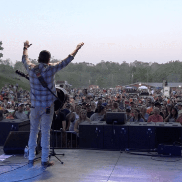 Singer raising hands on edge of stage