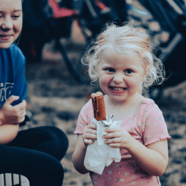little girl eating hot dog